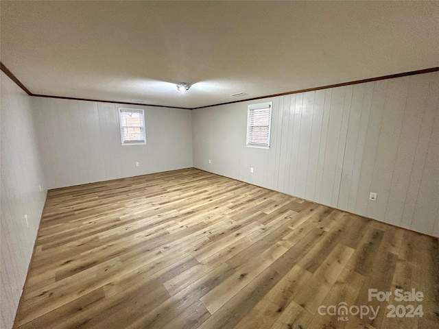 basement with wood walls, plenty of natural light, and light wood-type flooring