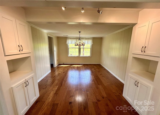 unfurnished dining area with ornamental molding, baseboards, dark wood-style flooring, and an inviting chandelier