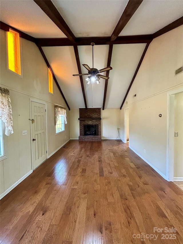 unfurnished living room with a fireplace, wood finished floors, a ceiling fan, and high vaulted ceiling