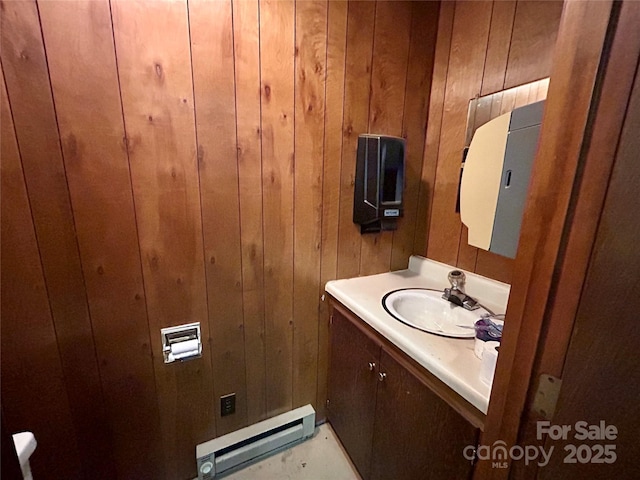 half bathroom featuring baseboard heating, wood walls, and vanity