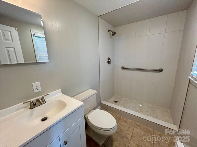 full bath featuring tiled shower, vanity, tile patterned floors, and toilet
