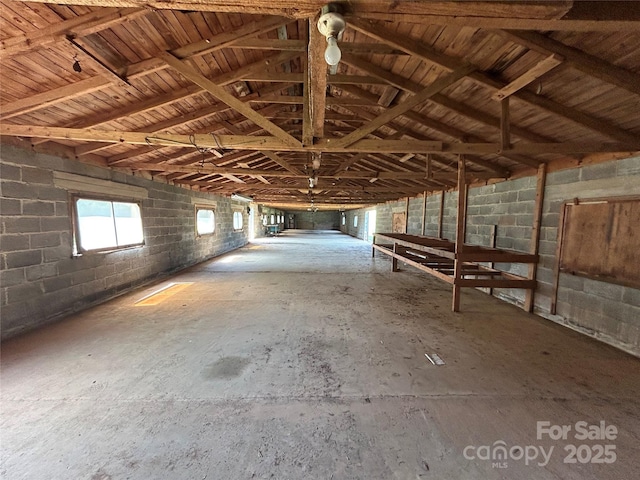 miscellaneous room featuring concrete block wall and lofted ceiling