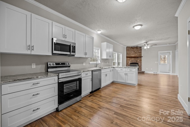 kitchen with stainless steel appliances, white cabinetry, ornamental molding, and light hardwood / wood-style flooring