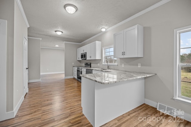 kitchen with sink, white cabinets, kitchen peninsula, stainless steel appliances, and light stone countertops