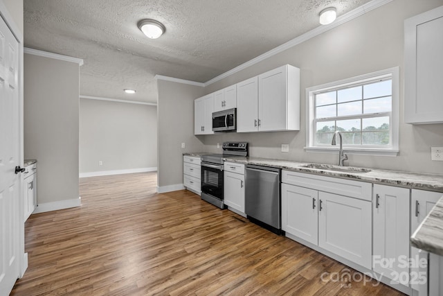 kitchen with sink, light hardwood / wood-style flooring, ornamental molding, stainless steel appliances, and white cabinets