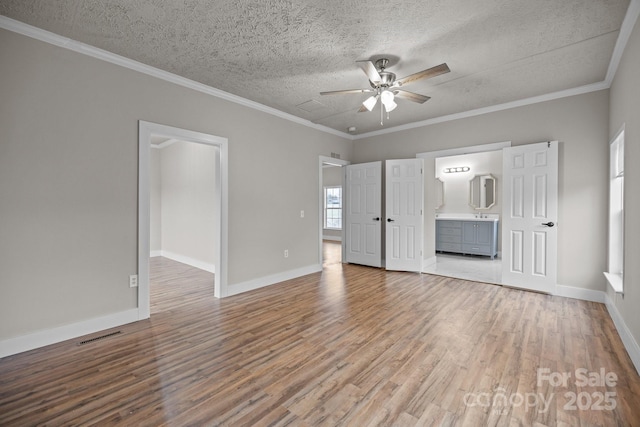 unfurnished bedroom featuring crown molding, wood-type flooring, ensuite bathroom, and a textured ceiling