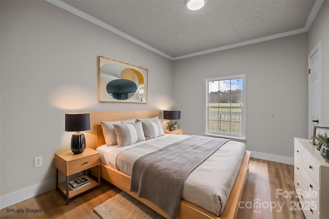 bedroom with ornamental molding, light hardwood / wood-style flooring, and a textured ceiling