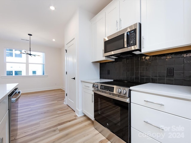 kitchen with backsplash, hanging light fixtures, light hardwood / wood-style flooring, white cabinetry, and stainless steel appliances