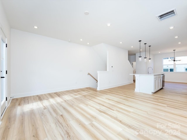 unfurnished living room with sink and light hardwood / wood-style flooring