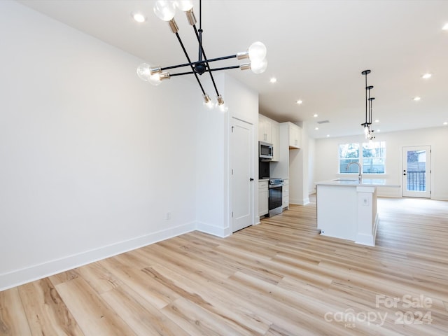 kitchen with pendant lighting, a kitchen island with sink, appliances with stainless steel finishes, light hardwood / wood-style floors, and white cabinetry