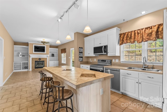 kitchen featuring appliances with stainless steel finishes, sink, a kitchen island, and white cabinets