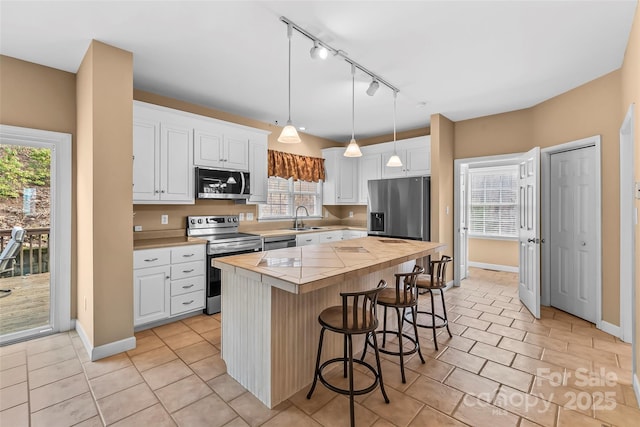 kitchen with sink, stainless steel appliances, white cabinets, and a kitchen island