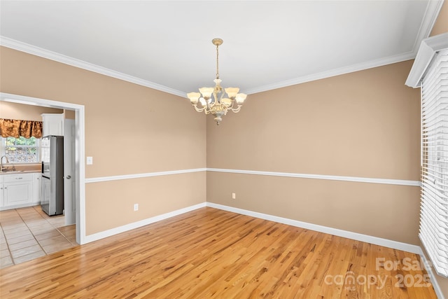 spare room featuring crown molding, sink, a notable chandelier, and light hardwood / wood-style floors