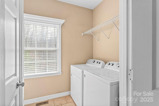 clothes washing area with washer and dryer and light tile patterned floors