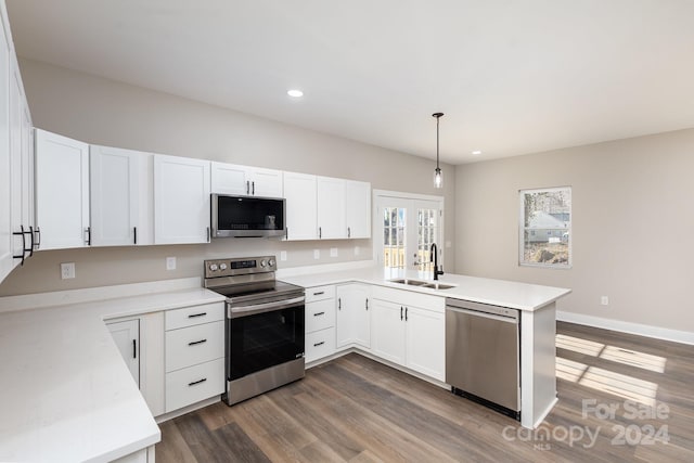 kitchen featuring kitchen peninsula, stainless steel appliances, sink, white cabinetry, and hanging light fixtures