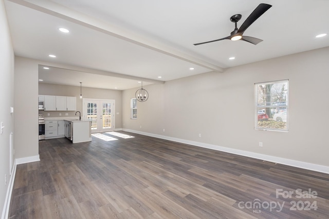 unfurnished living room with french doors, ceiling fan with notable chandelier, sink, dark hardwood / wood-style floors, and beamed ceiling