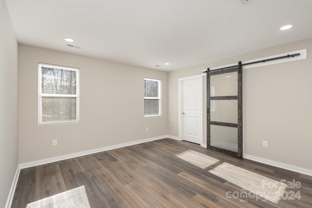 empty room featuring a barn door and dark hardwood / wood-style floors