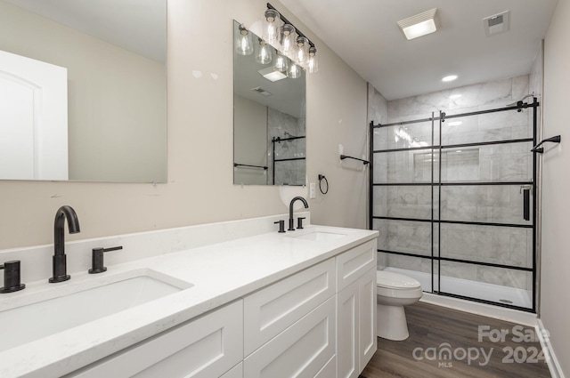 bathroom featuring wood-type flooring, vanity, toilet, and a shower with door