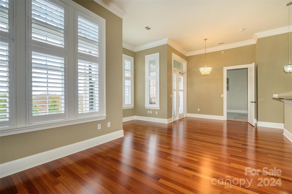 unfurnished room with crown molding, an inviting chandelier, and hardwood / wood-style flooring