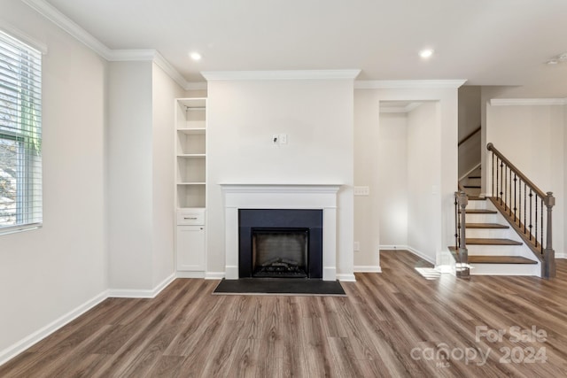 unfurnished living room with hardwood / wood-style floors, crown molding, and a wealth of natural light