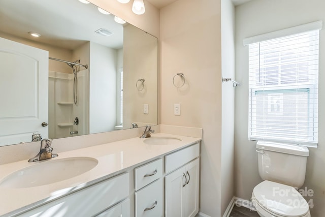 bathroom with a shower, plenty of natural light, vanity, and toilet