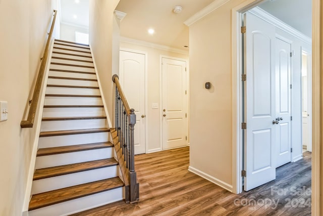 staircase featuring wood-type flooring and ornamental molding