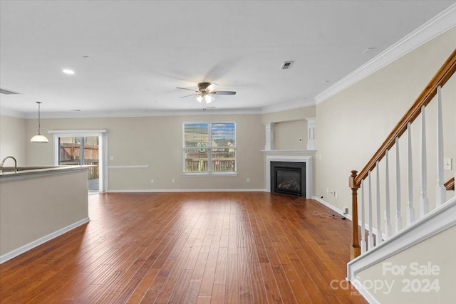 unfurnished living room with wood-type flooring, ceiling fan, ornamental molding, and sink