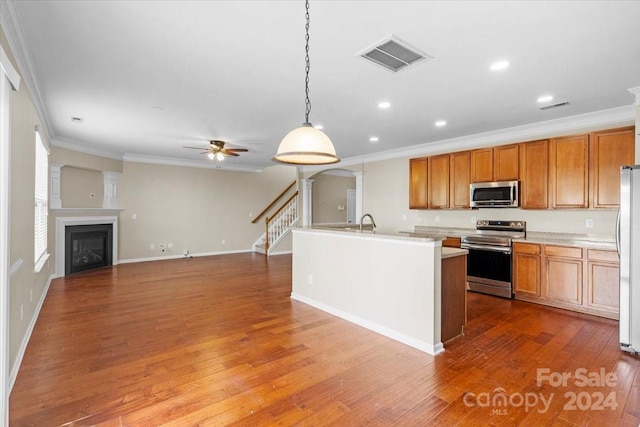 kitchen with pendant lighting, dark hardwood / wood-style flooring, stainless steel appliances, and crown molding