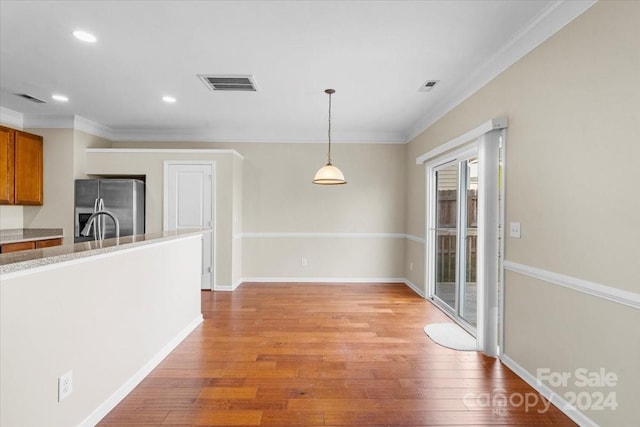 kitchen with pendant lighting, stainless steel fridge, light hardwood / wood-style floors, and crown molding