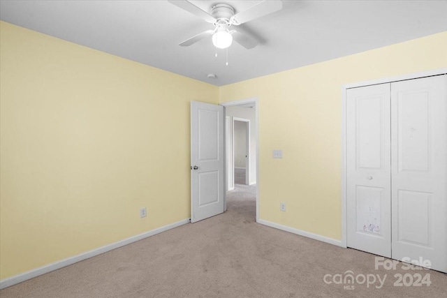 unfurnished bedroom featuring ceiling fan, light carpet, and a closet