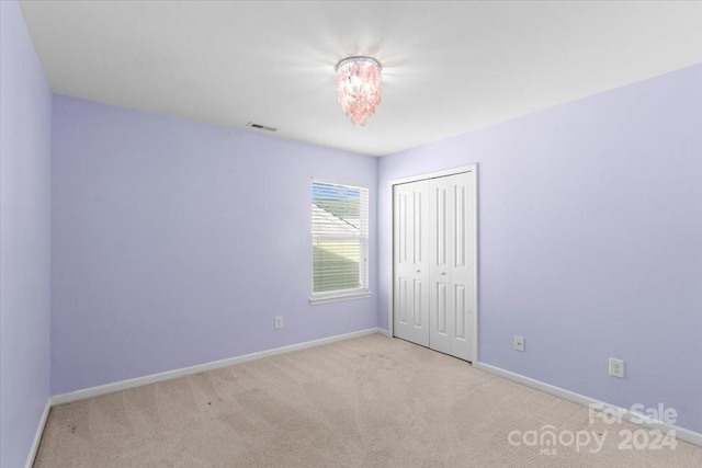 unfurnished bedroom featuring light carpet and a closet