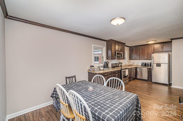 dining area with sink, hardwood / wood-style floors, and ornamental molding