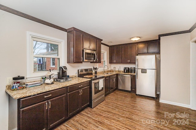 kitchen featuring appliances with stainless steel finishes, sink, dark brown cabinetry, and hardwood / wood-style floors