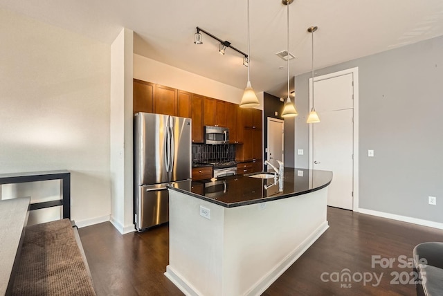 kitchen featuring backsplash, sink, an island with sink, decorative light fixtures, and stainless steel appliances