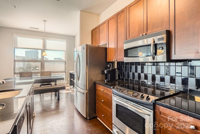 kitchen with tasteful backsplash, stainless steel appliances, dark wood-type flooring, sink, and decorative light fixtures