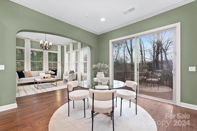 dining room with crown molding, hardwood / wood-style floors, and an inviting chandelier