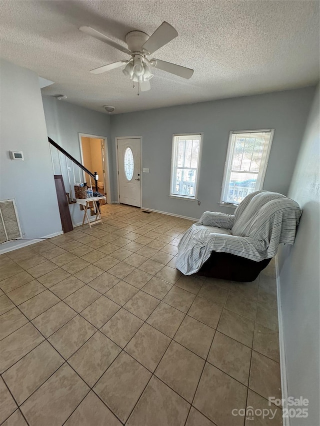 living room with light tile patterned flooring, a textured ceiling, and ceiling fan