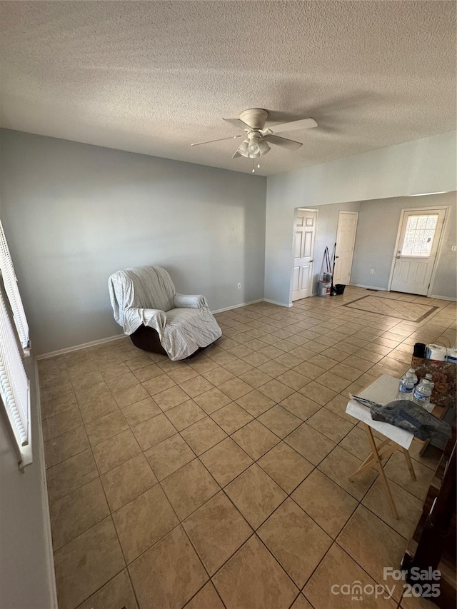 unfurnished room with ceiling fan, light tile patterned floors, and a textured ceiling