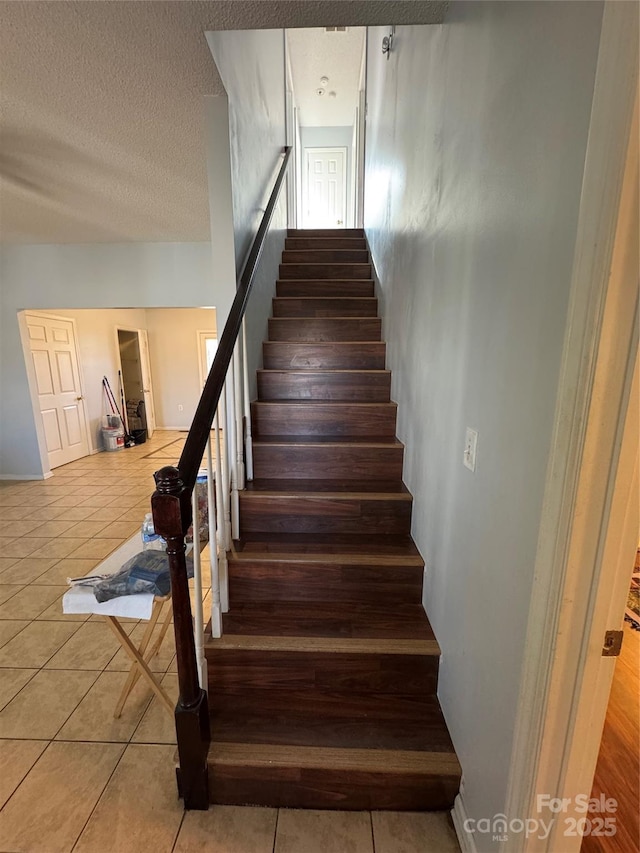 stairs with a textured ceiling and tile patterned floors