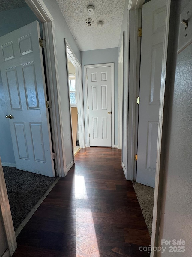 hall with dark wood-type flooring and a textured ceiling