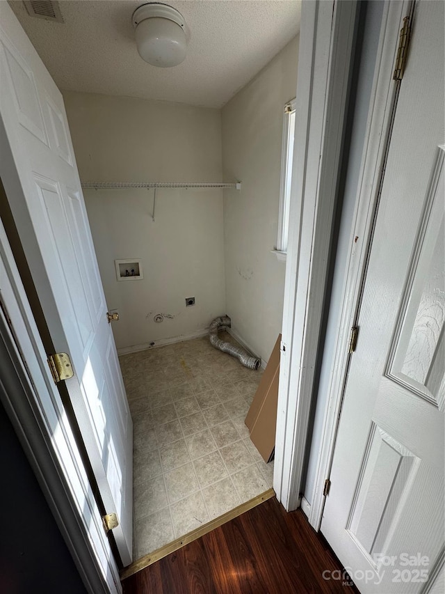 washroom with a textured ceiling, light hardwood / wood-style floors, and washer hookup