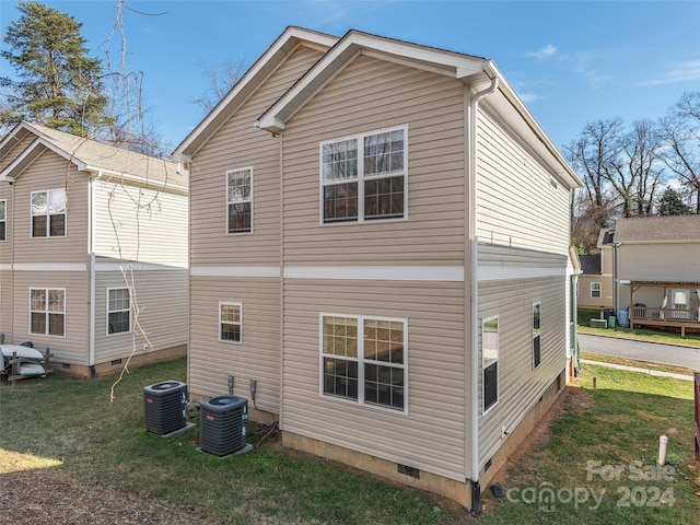 rear view of house with central AC and a yard