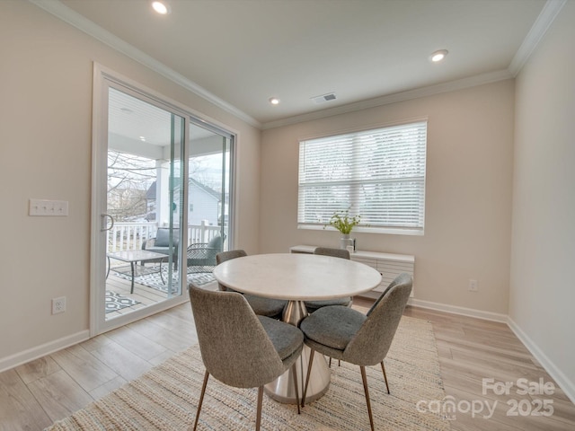 dining room with light wood-type flooring and ornamental molding