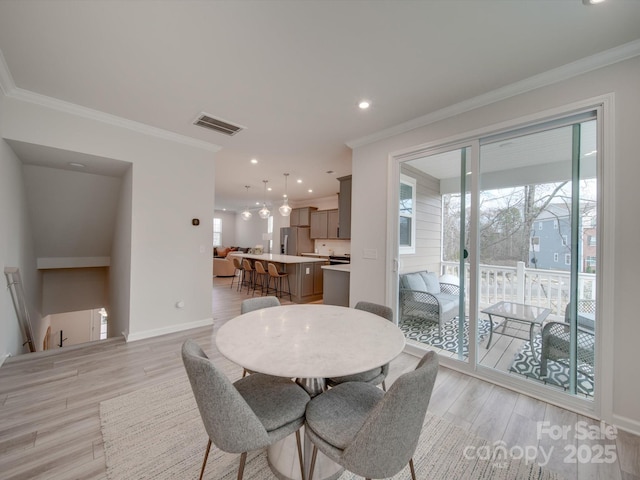 dining area featuring light hardwood / wood-style flooring, a healthy amount of sunlight, and ornamental molding