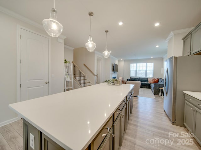 kitchen with stainless steel fridge, a center island, light hardwood / wood-style floors, and pendant lighting