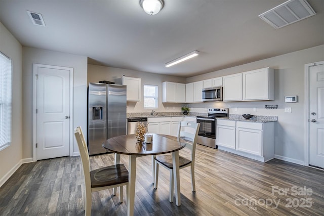 kitchen with white cabinets, dark hardwood / wood-style flooring, and stainless steel appliances