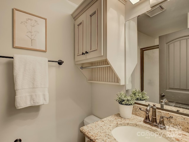 bathroom with vanity, a shower with shower door, and toilet