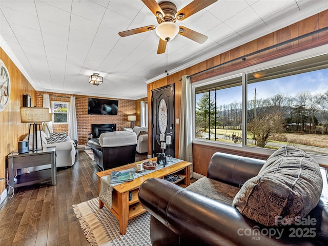 living room with dark wood-type flooring, plenty of natural light, brick wall, and ornamental molding