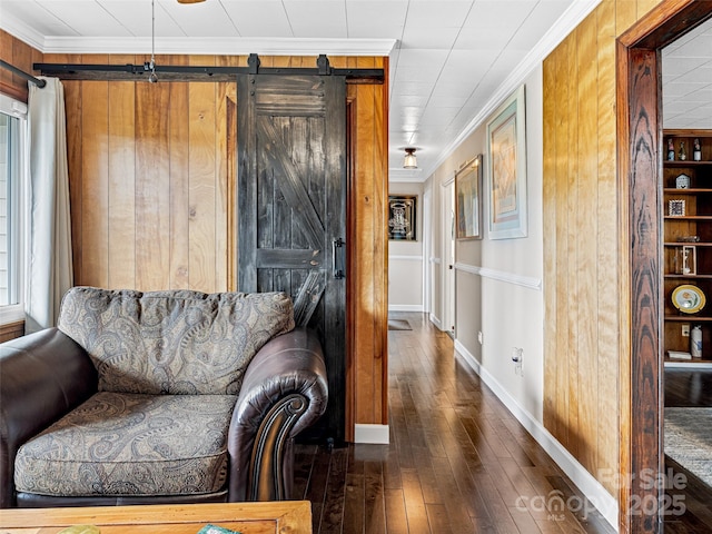 living room featuring a barn door, crown molding, and dark wood-type flooring