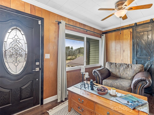 foyer entrance with a barn door, crown molding, plenty of natural light, and ceiling fan